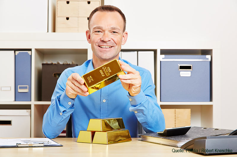 Mann hält Goldbarren Mann hält Goldbarren